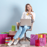 young lady using a laptop with gift bags sitting around her